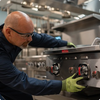 Technician adjusting the control knobs on a commercial range