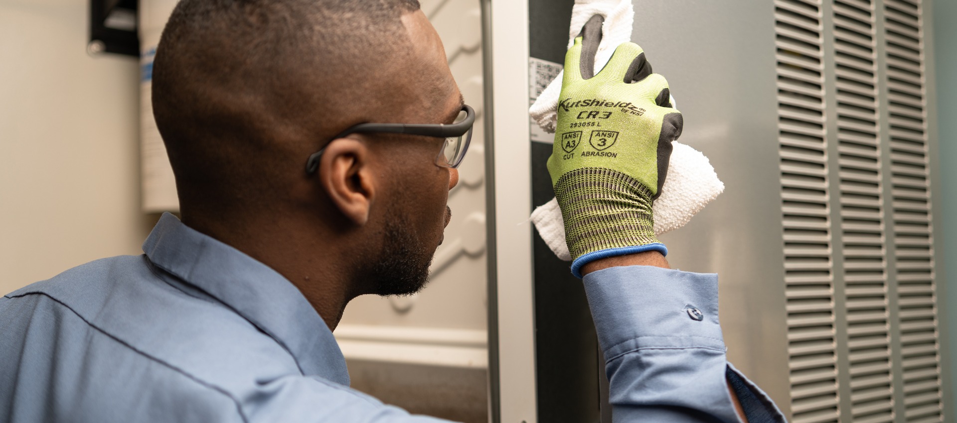 Technician in safety glasses examining a part while servicing commercial kitchen equipment