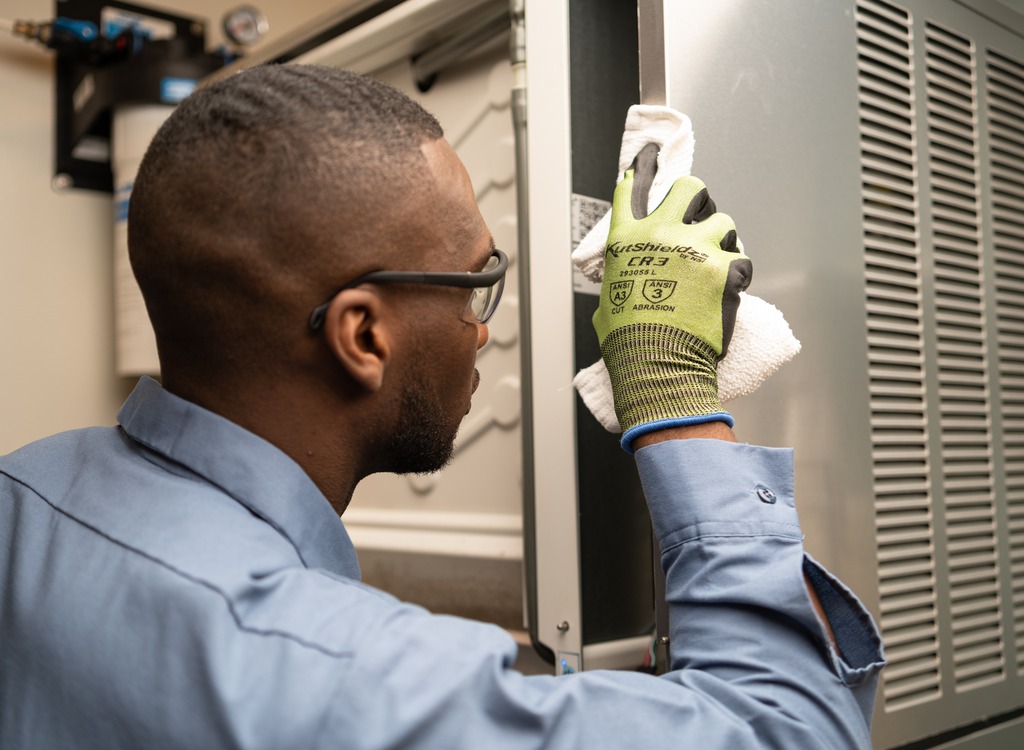 Technician in safety glasses examining a part while servicing commercial kitchen equipment