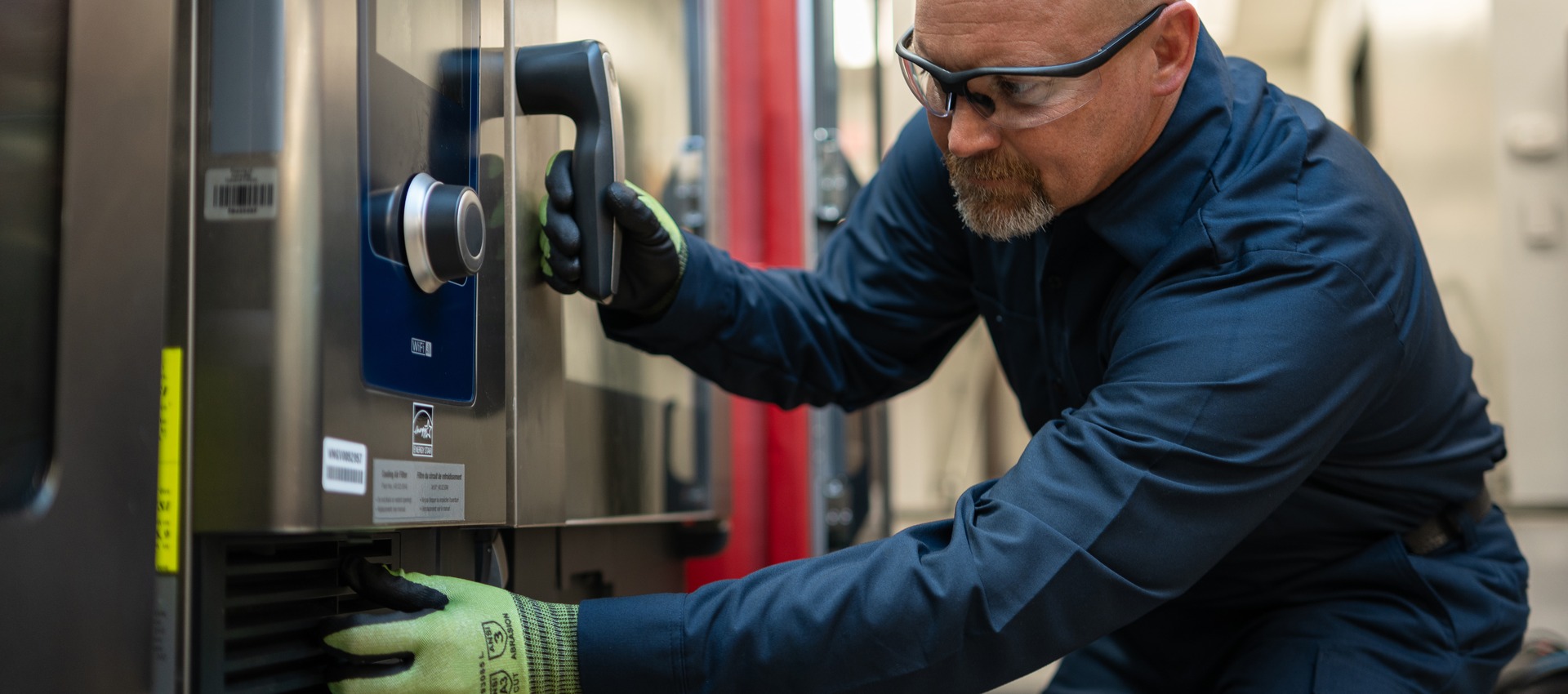 Technician in safety glasses servicing the controls of a commercial oven