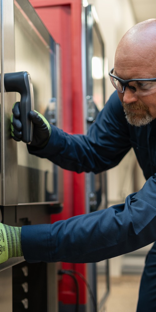 Technician in safety glasses servicing the controls of a commercial oven
