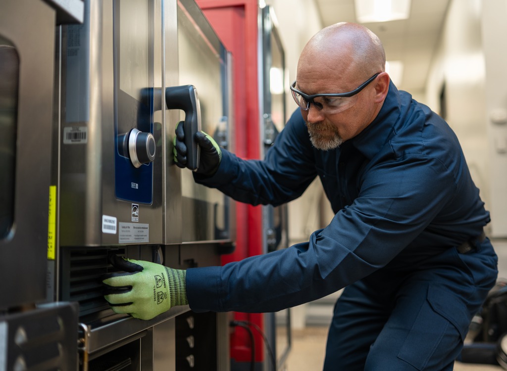 Technician in safety glasses servicing the controls of a commercial oven