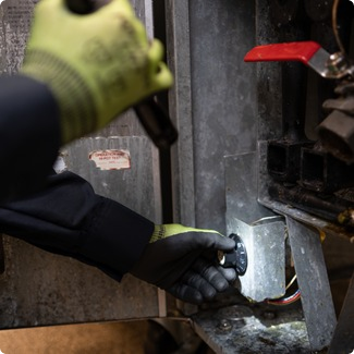 Gloved hands of a technician working on the internal components of a commercial kitchen appliance