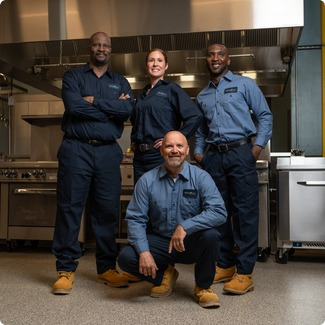 Total Tech service team of four technicians posing together in a commercial kitchen