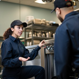 Total Tech technician talking through a repair with a colleague in a commercial kitchen