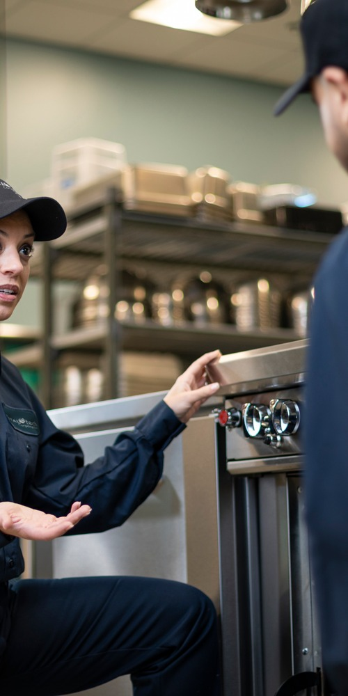 Total Tech technician talking through a repair with a colleague in a commercial kitchen