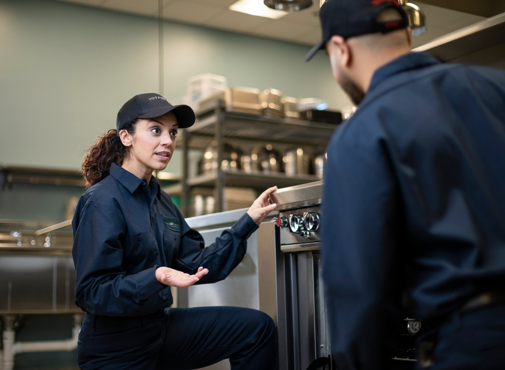 Total Tech technician talking through a repair with a colleague in a commercial kitchen